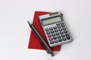 Na imagem, temos um papel com uma calculadora ao lado. Isso representa o calculo da receita média por cliente.