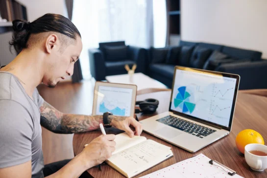 Empreendedor analisando informações sobre receitas, enquanto realiza o controle de pagamento de clientes.