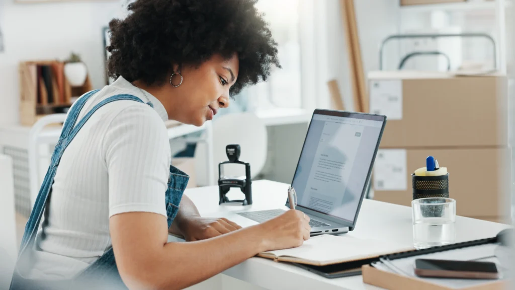 Empreendedora mexendo no computador e fazendo contas, enquanto aprende como calcular o capital de giro de sua empresa.