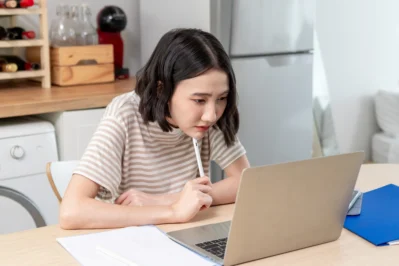 Mulher empreendedora sentada em frente ao computador. Está pesquisando o melhor banco para emitir boletos.