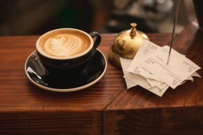 Na imagem, temos uma pessoa tomando café com vários papeis ao seu lado. Ela está entendendo a diferença entre os tipos de recibo.