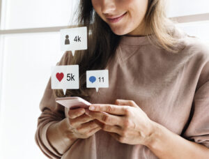 A imagem mostra a equipe do marketing com o celular na mão enquanto alguns icons do instagram saem da tela. Eles estão estudando como usar o instagram ads.
