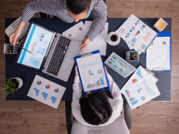 Uma equipe está no escritório, em volta de uma mesa, conversando sobre o plano de negócios.