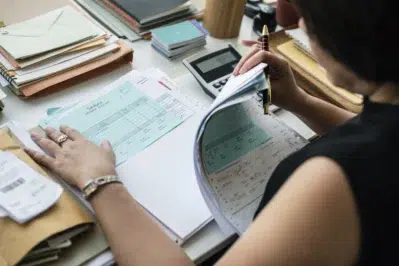 Empreendedora realizando a gestão financeira de sua empresa, visualizando os comprovantes de pagamento para a gestão de fluxo de caixa.