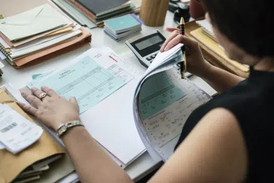 Empreendedora realizando a gestão financeira de sua empresa, visualizando os comprovantes de pagamento para a gestão de fluxo de caixa.