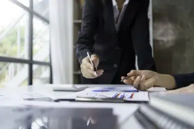 Empreendedores analisam planilhas em uma prancheta. Estão analisando a viabilidade e previsibilidade de receita.