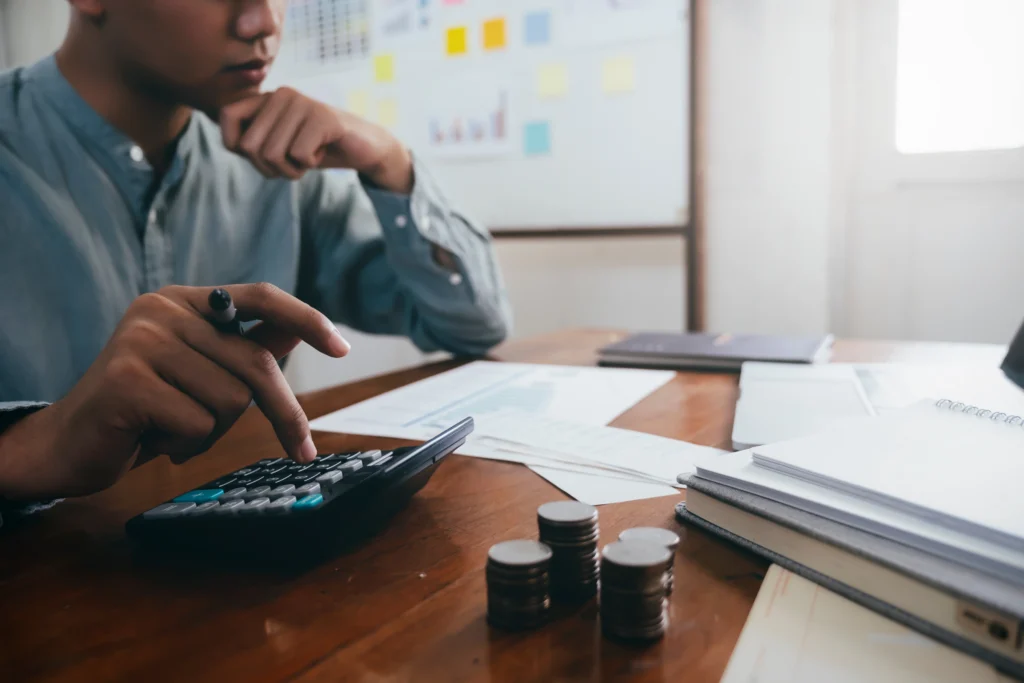 Homem usando calculadora e fazendo contas de taxa de boleto.