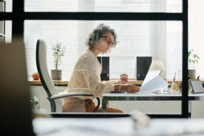 Mulher lendo a respeito da Lei da Duplicata, sentada em seu escritório.