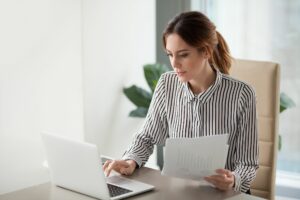 A imagem uma empresária em seu escritório, realizando operações financeiras em seu computador