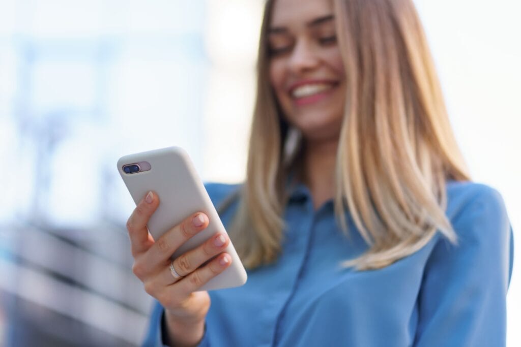 A imagem mostra uma empreendedora em seu celular, buscando por um aplicativo de cobrança gratuito