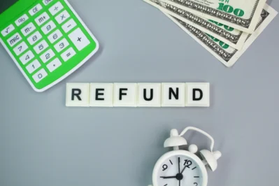 Imagem com a palavra "REFUND" em blocos, calculadora verde, relógio e dinheiro, representando reembolsos e como evitar chargeback.