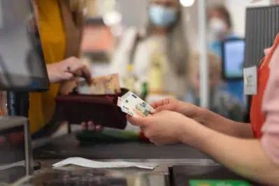 Pessoa recebendo dinheiro no caixa de um mercado utilizando o Pix Troco.