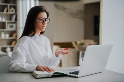 Mulher em frente ao notebook com expressão séria, gesticulando enquanto pesquisa como contestar um chargeback.