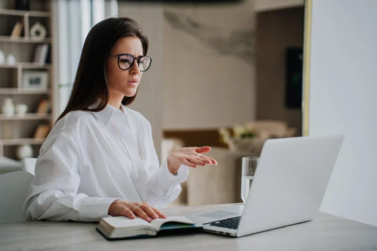 Mulher em frente ao notebook com expressão séria, gesticulando enquanto pesquisa como contestar um chargeback.