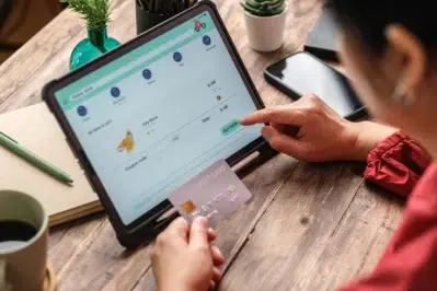 Mulher finalizando compra em um site via checkout online, utilizando-se do payment as a service da empresa.