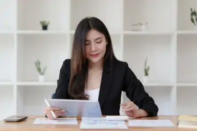 Mulher de negócios, de blazer preto, usando tablet em escritório, explorando o que é conta digital e como ela funciona.