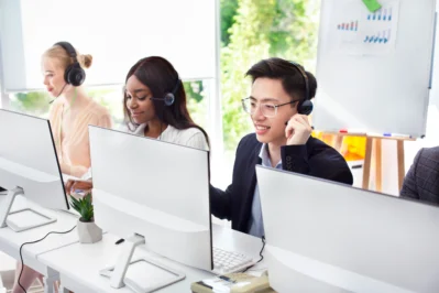 Três funcionários em frente aos seus computadores buscando como fazer cobrança de clientes.