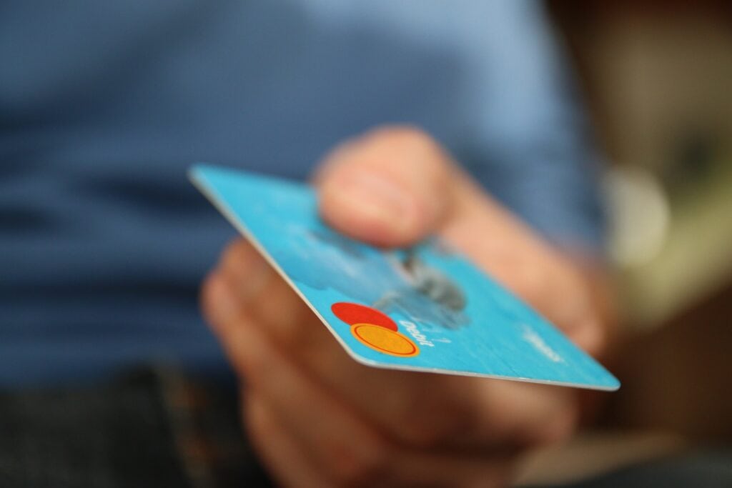 Homem segura um cartão de crédito na mão. A imagem busca representar como sacar o limite do cartão de crédito.