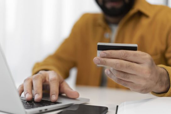 Empreendedor mexendo no computador, inserindo os dados do seu cartão de crédito na plataforma de pagamentos