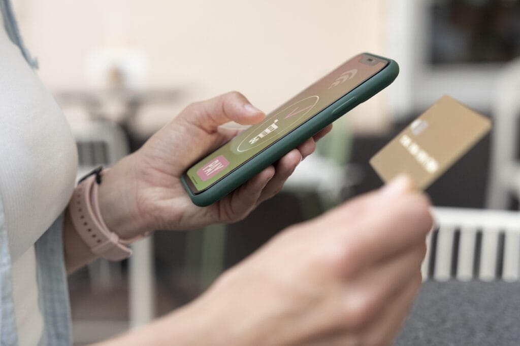 Uma pessoa segura o segura o celular enquanto cadastra os dados do seu cartão. Ela está esperando seu cliente pagar para receber pagamentos sem maquininha.