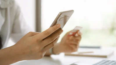 Mãos segurando o celular e um cartão, representando como receber pagamentos sem maquininha.