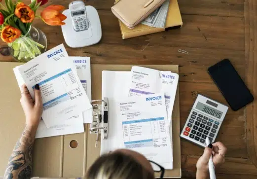 Pessoa conferindo faturas e usando calculadora, representando o processo de como gerar boleto parcelado de forma prática.