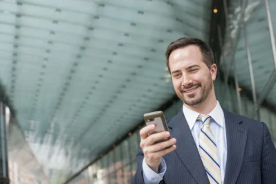 Homem de negócios, de terno e gravata, sorrindo ao utilizar um aplicativo de conta digital.
