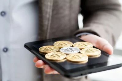 Imagem mostra moedas de ouro em cima de um tablet, simbolizando o real digital.