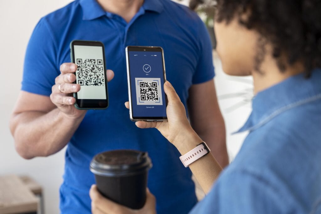 Na imagem, temos um empreendedor com o celular na mão, mostrando um QR code para um cliente que aponta o seu celular para leitura do QR code. Representando como funciona o golpe do Pix.