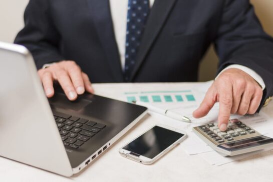 Na imagem, temos um homem mexendo em seu computador no escritório. Ele está pesquisando sobre como fazer gestão financeira para igrejas.