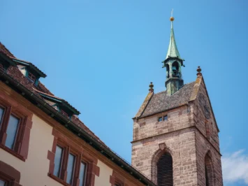 Torre de igreja histórica com relógio e telhado inclinado sob céu azul. A gestão financeira para igrejas é essencial para sua preservação.