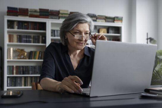 Uma diretora está pesquisando sobre gestão financeira escolar no computador de sua sala.