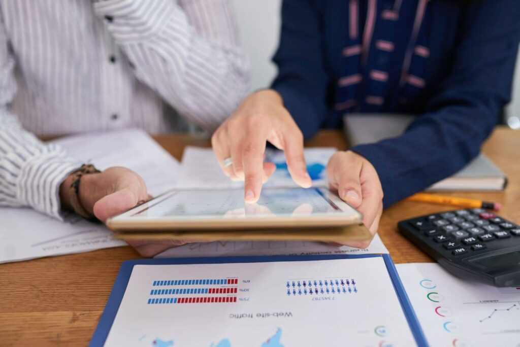 Dois empreendedores estão mexendo em um tablet. Eles estão buscando como funciona a gestão financeira para startups