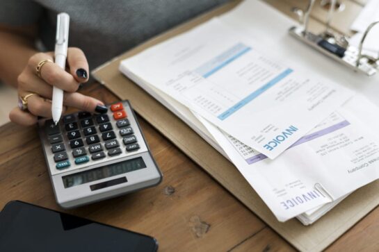 Mãos sobre a mesa, organizando os dados para a nota fiscal.