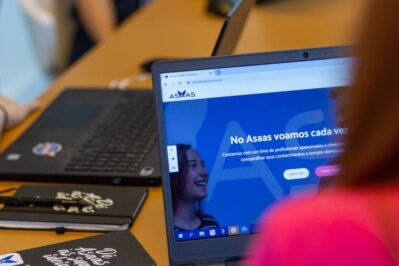 Uma empreendedora está em seu escritório, gerenciando seus contratos. Ela está ativando a notificação de cobrança do Asaas.