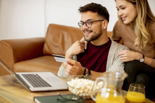 Casal está em frente ao computador buscando o que é pagamento trimestral para fazer assinatura.