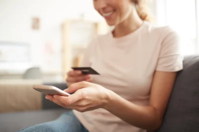 A mulher segura o celular sorrindo, pois descobriu o que é link de pagamento.