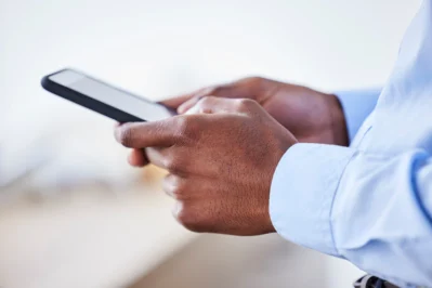 Homem segurando o celular após receber uma cobrança pelo whatsapp.