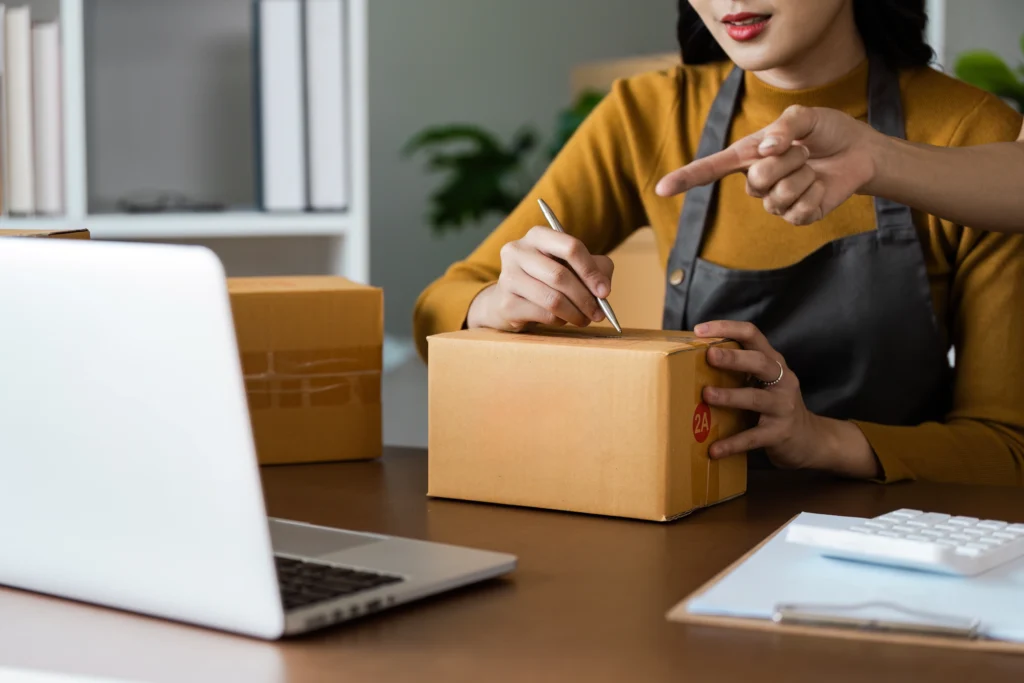 Mulher com caixa de envio de mercadoria, buscando como gerar boleto para receber pagamento.