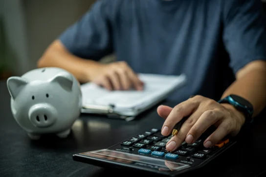 homem fazendo contas em calculadora, com um cofrinho ao lado, representando como manter um fluxo de caixa saudável.