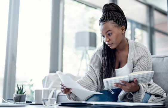 Mulher concentrada revisando documentos financeiros e faturas, exemplificando como sair das dívidas de maneira eficaz.