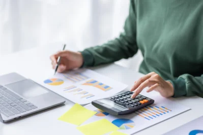 Mulher analisando papelada sobre o que é demonstrativo financeiro e mexendo na calculadora.