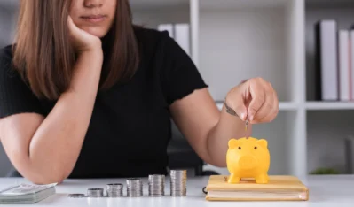 mulher colocando dinheiro em cofre e aprendendo como conquistar a independência financeira.