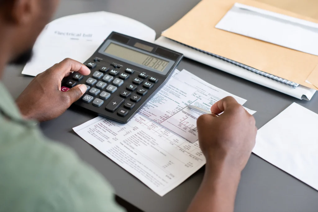 Homem usando calculadora e aprendendo como organizar as finanças pessoais.