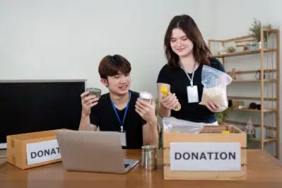Voluntários realizando a gestão da conta digital para ONG, verificando produtos e preenchendo informações no computador.