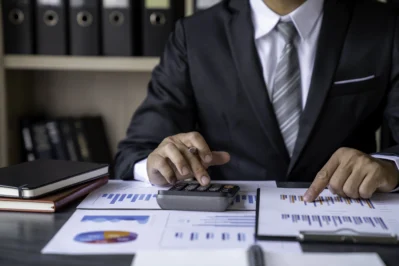 Empresário utilizando calculadora e analisando gráficos, enquanto aprende o que é capital de giro.