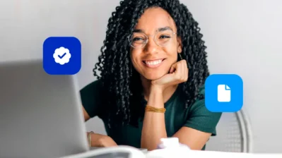 Moça sorri para a câmera, ela tem um notebook na sua frente com o guia para regularizar empresa.