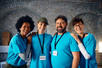 Grupo de voluntários sorrindo com crachás, representando ações sociais e a dúvida comum se associação paga imposto ou não.