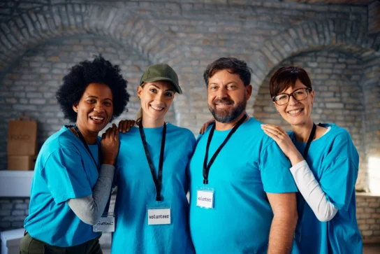 Grupo de voluntários sorrindo com crachás, representando ações sociais e a dúvida comum se associação paga imposto ou não.