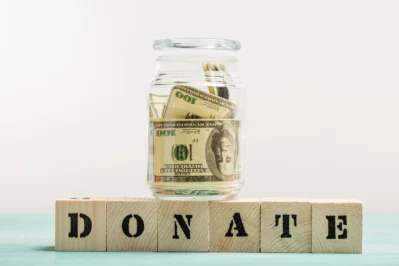 Pote com dólares e blocos escrito "Donate", representando como declarar doação recebida na declaração de imposto de renda.